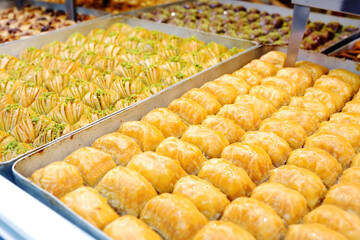 Assortment of traditional turkish dessert baklava on a showcase of shop. Sweets as a food background. Texture.