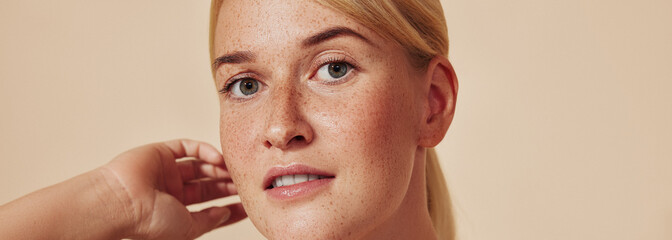 Cropped shot of a young beautiful blond woman with freckles. High-detailed portrait of a female with smooth freckled skin against a pastel backdrop.