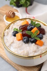 Delicious barley porridge with blueberries, pumpkin, dates and mint in bowl on table, closeup