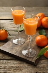 Delicious tangerine liqueur and fresh fruits on wooden table