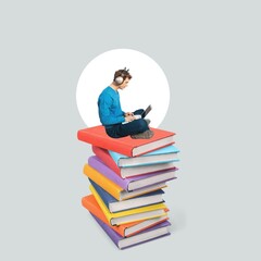 A man holds laptop sits on huge stack books.
