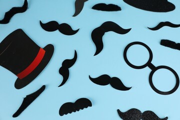 Fake mustaches, hat and glasses on light blue background