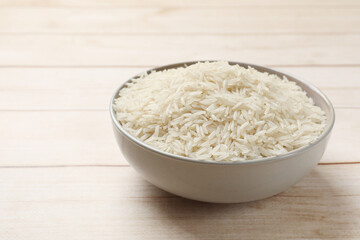 Raw basmati rice in bowl on white wooden table