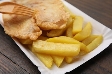 Delicious fish and chips served on wooden table, closeup