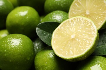 Fresh limes and leaves with water drops as background, closeup