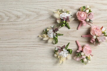 Stylish boutonnieres on white wooden table, flat lay. Space for text