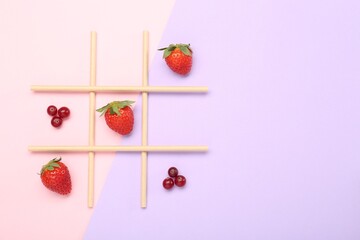 Tic tac toe game made with berries on color background, top view. Space for text