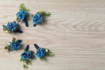 Stylish blue boutonnieres on white wooden table, flat lay. Space for text