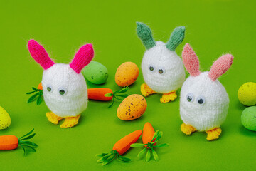 Handmade Easter concept. Knitted bunnies with traditional decoration. Festive symbols, greeting card