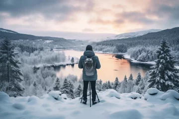 Fotobehang Lone photographer stands amidst a serene, snow-covered forest landscape at sunrise © Татьяна Евдокимова