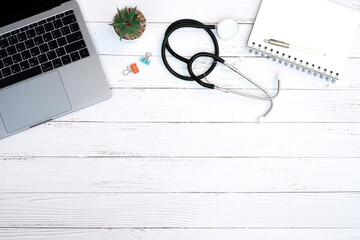Flat lay, medical technology and healthy concept on modern white table desk background with stethoscope and laptop computer, blank notepad, supplies, Top view with copy space