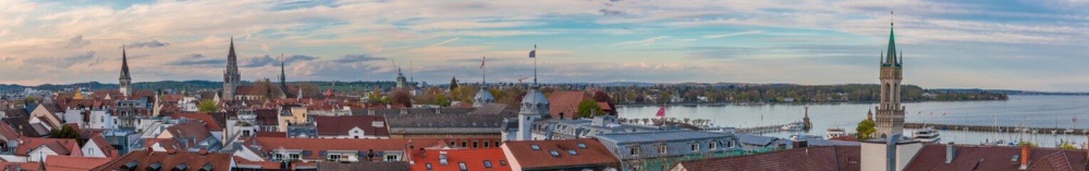 Huge panoramic view over the city Constance (Konstanz) by Lake Constance (Bodensee). The Imperia statue, the towers of church St. Stephan, Constance Cathedral and the train station can be seen. - obrazy, fototapety, plakaty