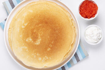 Pancakes with red caviar and sour cream, Close-up of pancakes stacked on white background