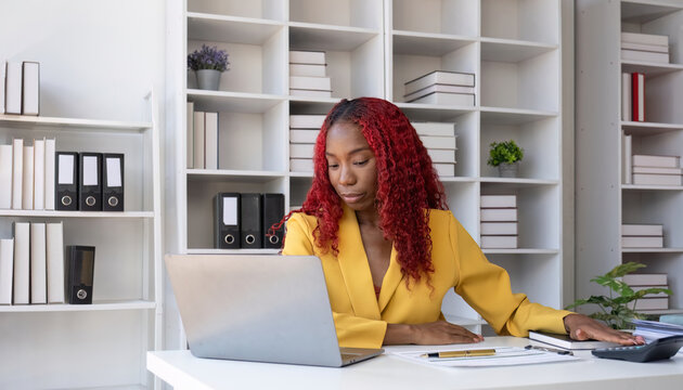 African American businesswoman is unhappy sitting on her office desk doing accounting and finance work.