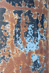 Abstract art created from the textured surface of  blue paint peeling off aged old grungy, red rusty metal.