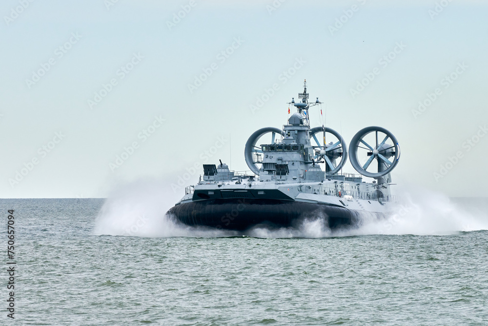 Wall mural Hovercraft warship armed with armament sails into sea toward military target to attack and destroy enemy, military hovercraft ship performing strategic maneuver, Russian sea power deployment