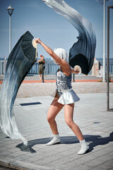 Young sexy girl in space silver micro skirt dancing with performance fan waving gracefully, female...