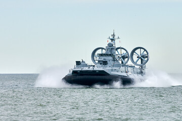 Hovercraft warship armed with armament sails into sea toward military target to attack and destroy...