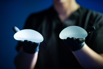 Surgeon hands showing silicone breast implants.