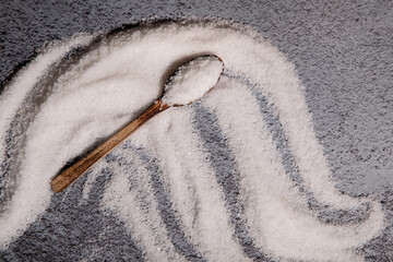 wooden spoon with salt lies on the salt scattered on the table