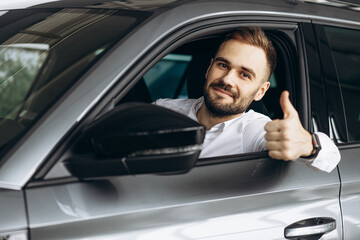 Business man sitting in his new car in car showroom