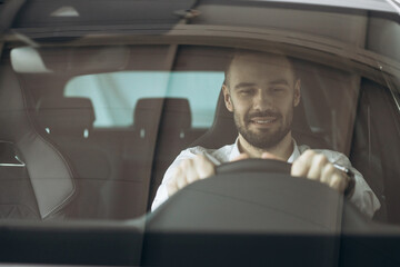 Man sitting in his new car in car showroom