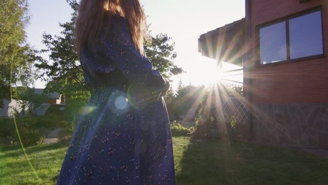 Beautiful pregnant woman enjoying fresh air at sunset rays on the backyard