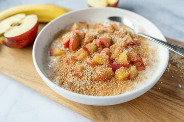Healthy breakfast with a banana yogurt. Topped with puffed amaranth and cooked apples in a bowl
