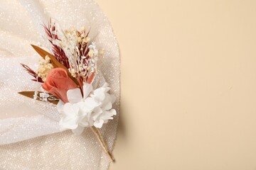 Stylish boutonniere and white fabric on beige background, top view. Space for text © New Africa
