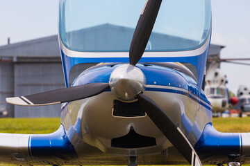 Front view to propeller of light two-seat single-engine aircraft on blurred background.