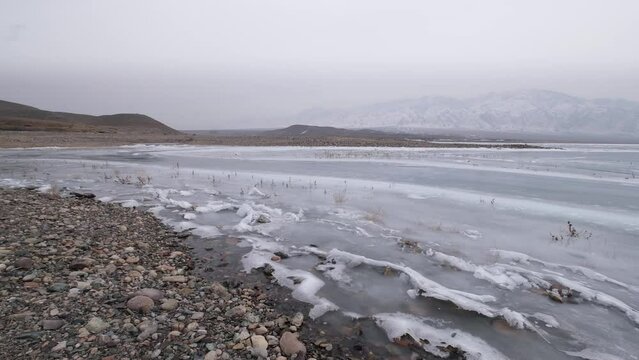 Mountain lake covered with ice, snow and hummocks in early spring. Bartogay reservoir in Kazakhstan.