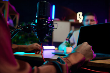 Focus on female hands, microphone and laptop. Blogger making online podcast show, discussing interesting lifestyle topics. Concept of online communication, modern technology, mass media