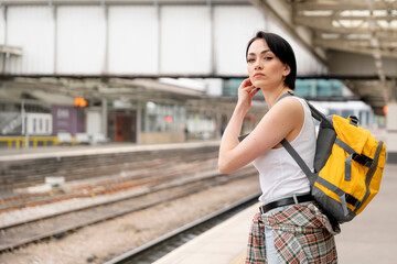 woman with a backpack while at the train station and the train is arriving. Enjoying travel concept