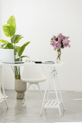 Business concept. Light work place of accountant at office with desk table, laptop, financial documents folder calculator, eyeglasses, smartphone, pen and big green houseplant. Copy space on wall