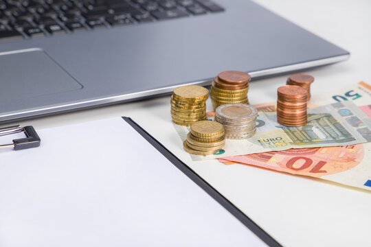 laptop, coins and banknote on a desk.