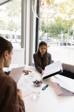 Female real estate agent explaining floor plan to customers in office