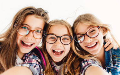 
Three cute young girls having fun together, taking a selfie on a white background
