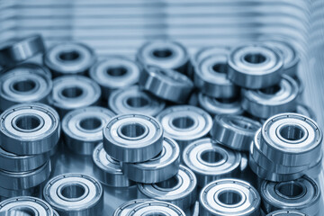 Close up scene the pile of cylindrical ball bearing parts in the light blue scene.