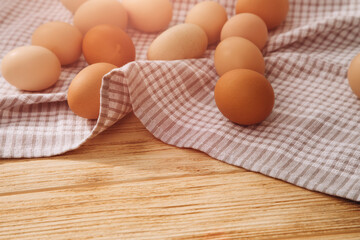 Chicken eggs of different brown and beige shades on a wooden background on grey kitchen towel. Easter background. Top view