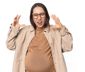 Pregnant young Caucasian woman showcasing maternity on studio background screaming with rage.