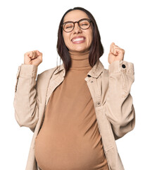 Pregnant young Caucasian woman showcasing maternity on studio background celebrating a victory,...