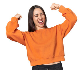 Modern young Caucasian woman portrait on studio background raising fist after a victory, winner...