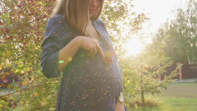 Beautiful pregnant woman having walk in the park
