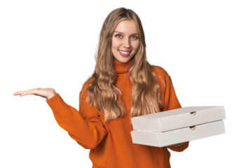 Blonde woman holding pizza boxes in studio showing a copy space on a palm and holding another hand on waist.