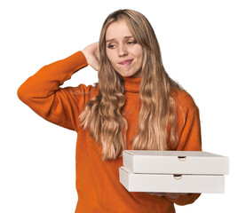 Blonde woman holding pizza boxes in studio touching back of head, thinking and making a choice.