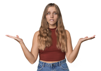 Studio portrait of a blonde Caucasian woman confused and doubtful shrugging shoulders to hold a copy space.