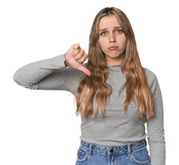 Studio portrait of a blonde Caucasian woman showing a dislike gesture, thumbs down. Disagreement concept.