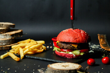 Hamburger With Knife Next to French Fries