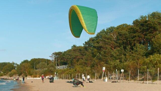 A paraglider is preparing to take off on a sandy beach in summer. Gdansk. Paragliding in Poland over the Baltic Sea against a clear blue sky
