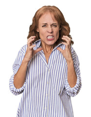 Redhead mid-aged Caucasian woman in studio upset screaming with tense hands.